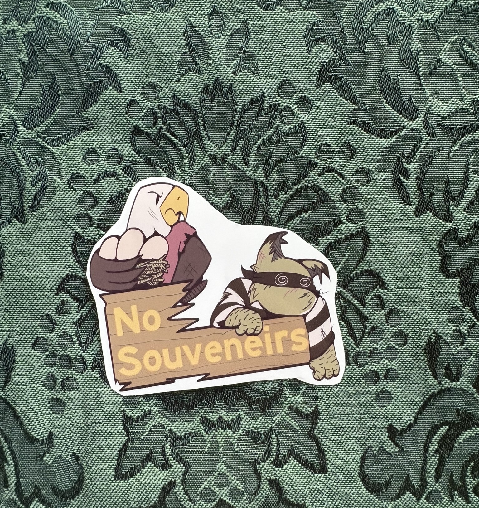 An eagle blocks a beaten-down bobcat from stealing their eggs. Text reads NO SOUVENEIRS